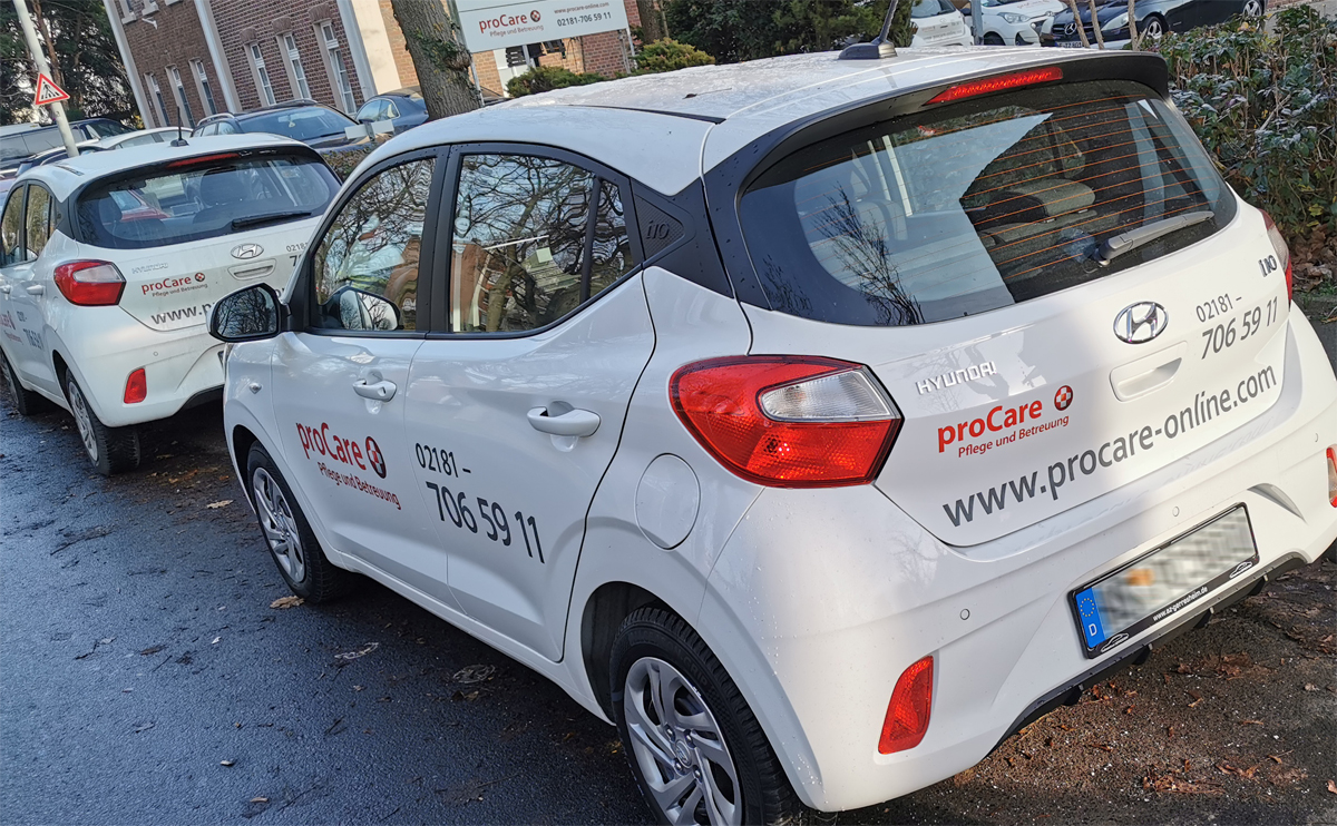 Autobeschriftung eines Hyundai i10 mit roter und grauer Folienschrift, sowie partiellen Digitaldruckaufklebern für das Pflege- und Beratungsunternehmen proCare in Grevenbroich-Elsen.