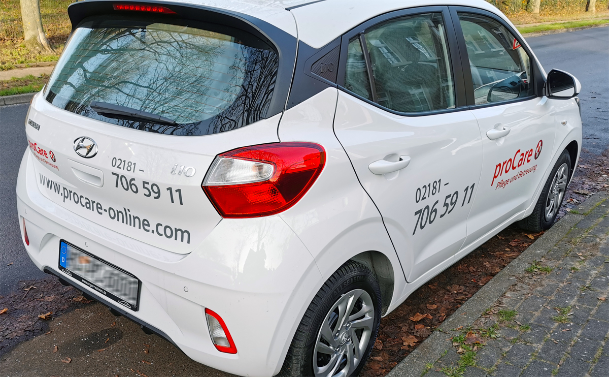 Autobeschriftung eines Hyundai i10 mit roter und grauer Folienschrift, sowie partiellen Digitaldruckaufklebern für das Pflege- und Beratungsunternehmen proCare in Grevenbroich-Elsen.